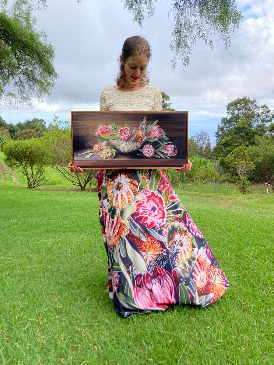 Julia Allisson Cost in a skirt of her Protea Bouquet fabric, holding the painting it was made from