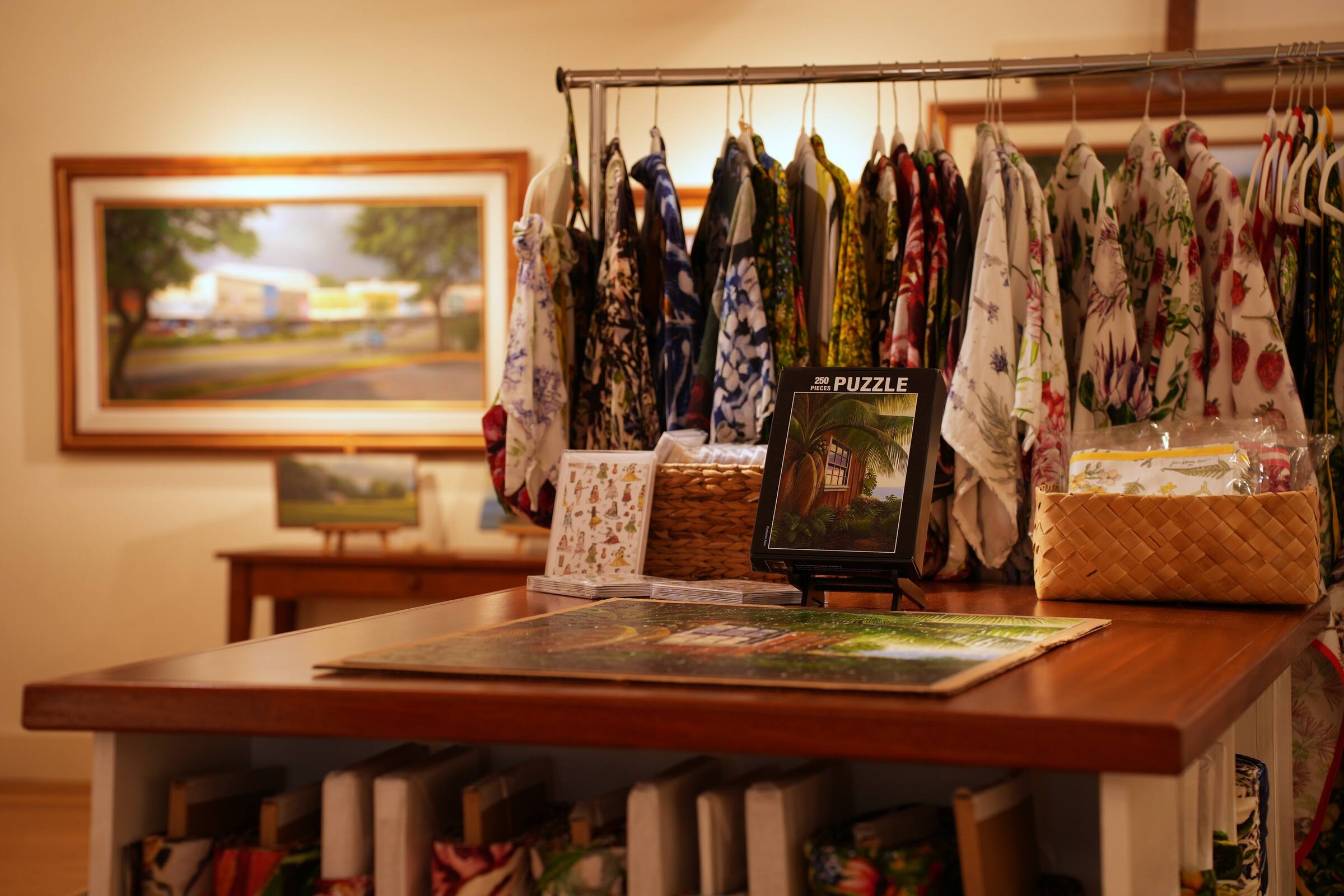A rack of aloha shirts behind a table of puzzles and cards