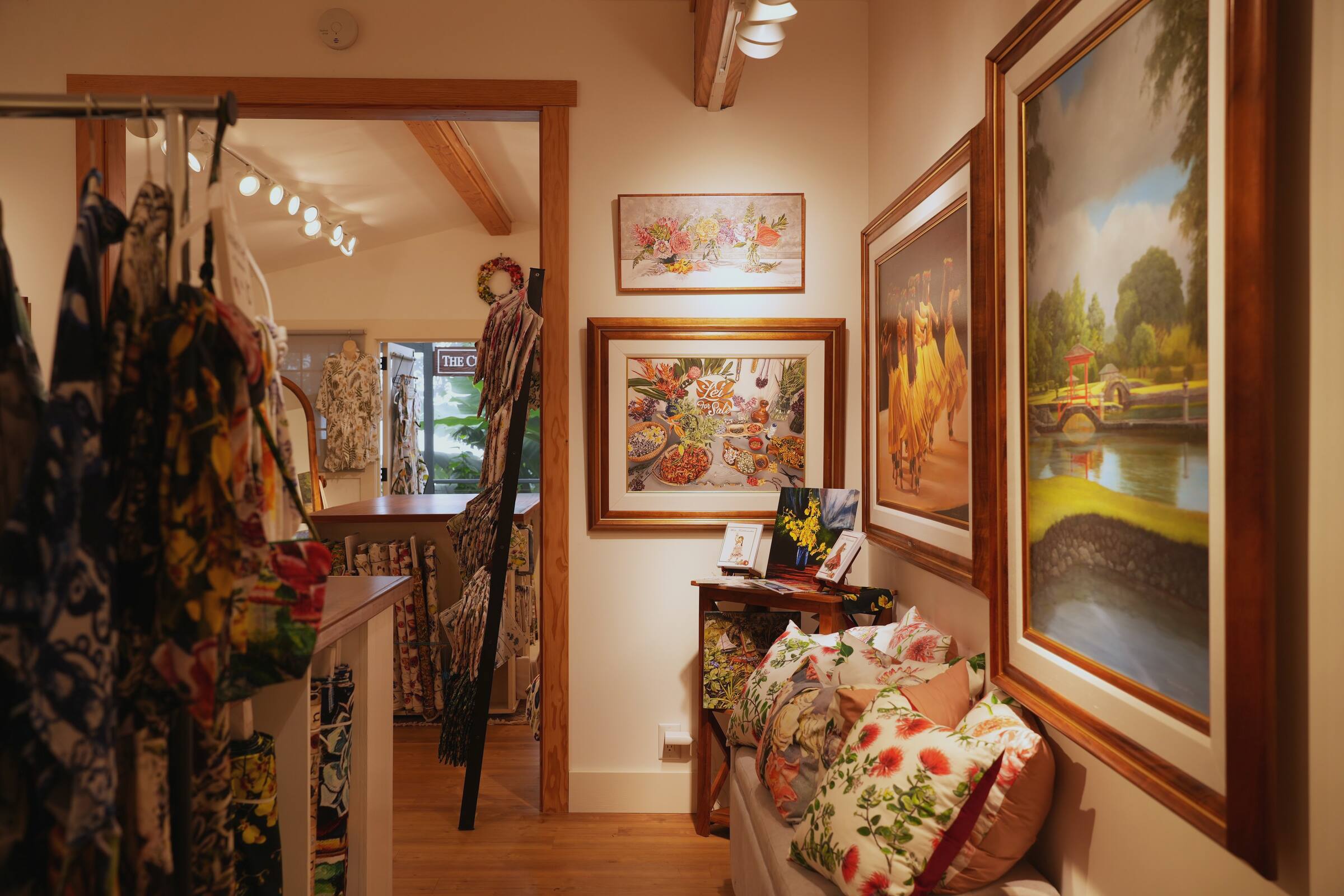 Framed paintings and cushions by the doorway through to the shop