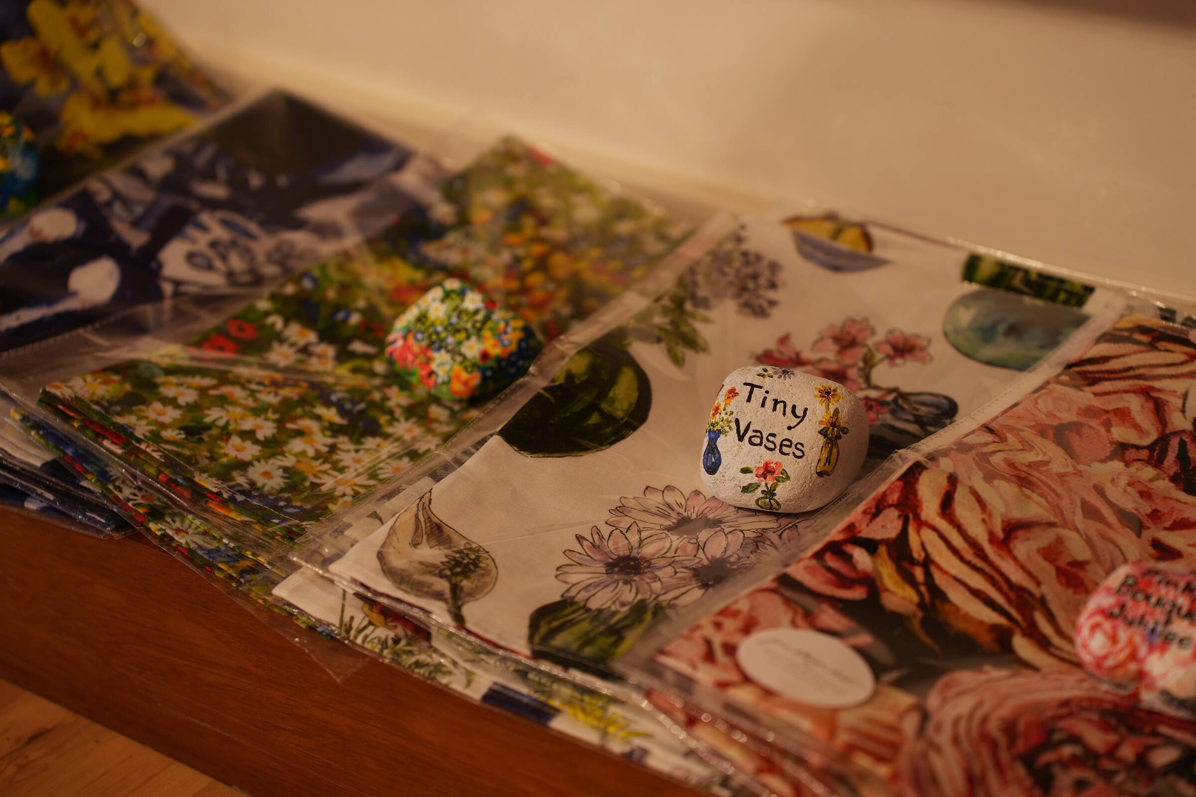 Fabric and printed gifts, with a painted stone reading Tiny Vases